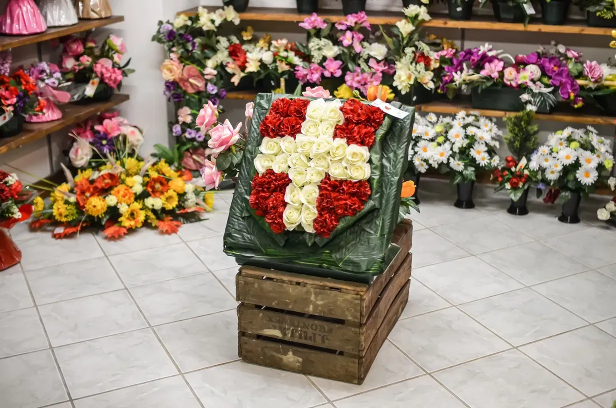 Composition florale représentant une croix rouge et blanche exposée en magasin